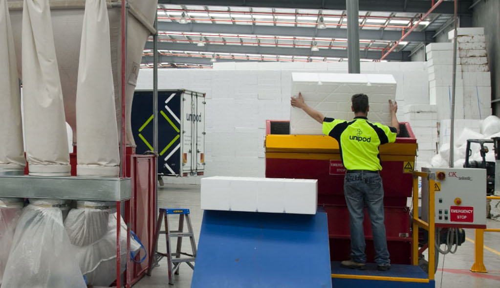 Worker guiding a waffle pod into an expanded polystyrene recycling machine